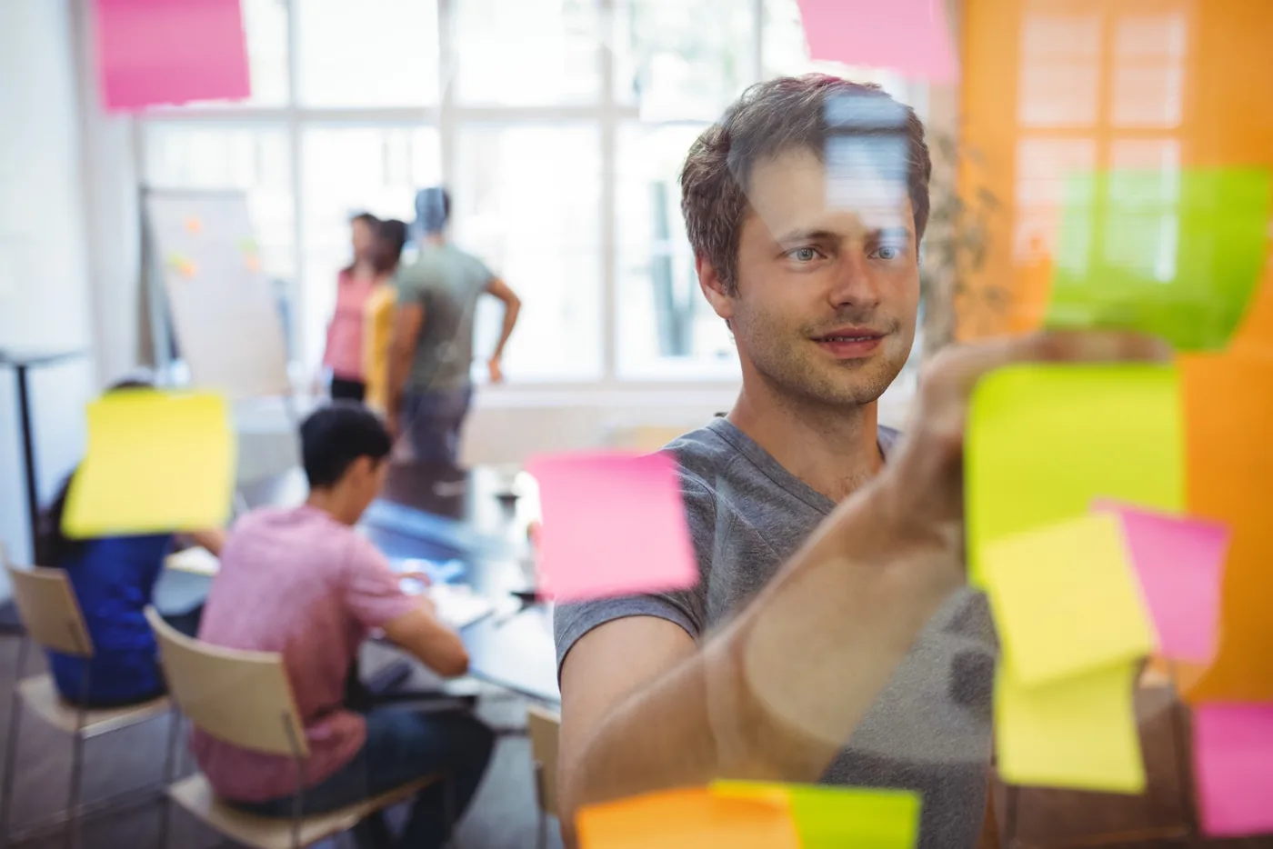 Persona organizando tareas con notas en un espacio de trabajo